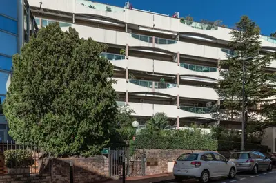 a white building with cars parked in front of it at Le Charme YourHostHelper in Cannes