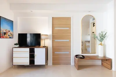 a living room with a television on a dresser with a mirror at Le Charme YourHostHelper in Cannes