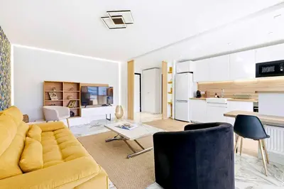 a living room with a yellow couch and a kitchen at Lacour - 2 bedroom apartment - Large terrace - 2 min from the Croisette & beaches in Cannes