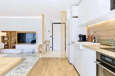 a kitchen with white cabinets and a television at Lacour - 2 bedroom apartment - Large terrace - 2 min from the Croisette & beaches in Cannes