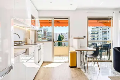 a kitchen with white counters and a table and chairs at Lacour - 2 bedroom apartment - Large terrace - 2 min from the Croisette & beaches in Cannes