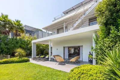 a white house with two chairs in a yard at Luxury Two-Storey Villa with Pool & Rooftop Peaceful Setting Near Cannes in Cannes