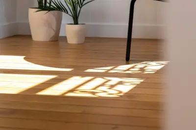 a shadow of a table and two plants on a wooden floor at Riviera signature apartment by Welcome to Cannes in Cannes