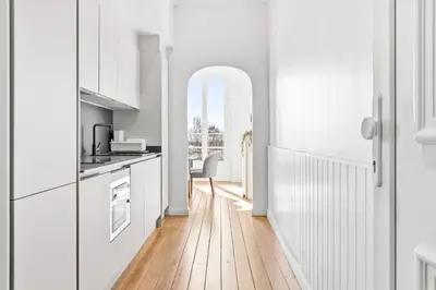 a kitchen with white cabinets and a wooden floor at Riviera signature apartment by Welcome to Cannes in Cannes
