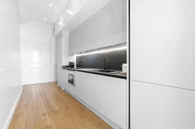a kitchen with white appliances and a wooden floor at Riviera signature apartment by Welcome to Cannes in Cannes
