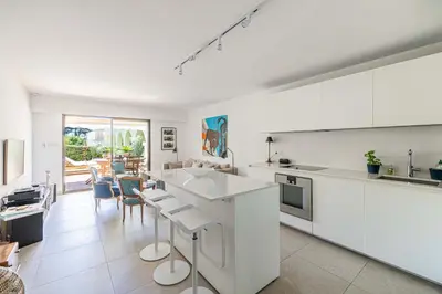 a kitchen with white appliances and a living room at LE PARADIS avec deux terrasses équipées et piscine in Cannes