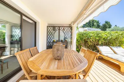 a wooden table and chairs on a wooden deck at LE PARADIS avec deux terrasses équipées et piscine in Cannes