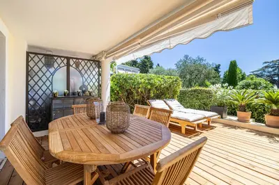 a wooden table and chairs on a wooden deck at LE PARADIS avec deux terrasses équipées et piscine in Cannes