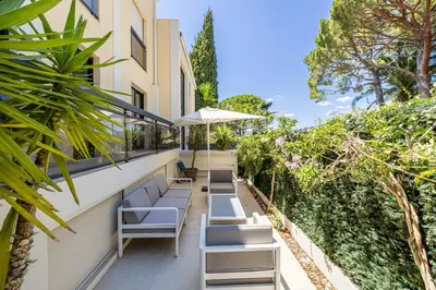 an outdoor patio with chairs and an umbrella at LE PARADIS avec deux terrasses équipées et piscine in Cannes