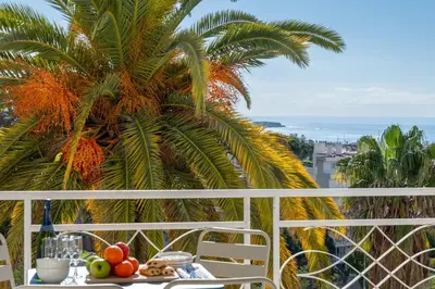 a table with fruit on a balcony with a palm tree at 2-Br Sea-View Apartment Residence with Swimming Pool Cannes in Cannes