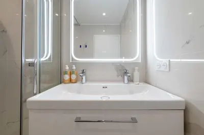 a white bathroom with a sink and a mirror at 2-Br Sea-View Apartment Residence with Swimming Pool Cannes in Cannes