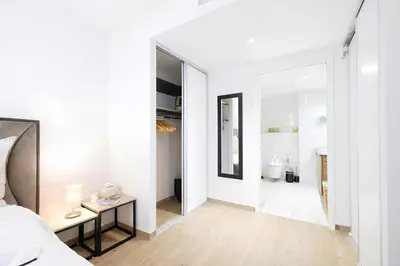 a white bedroom with a bed and a bathroom at Sud Croisette - Proche Palais des Festivals in Cannes