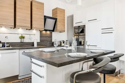 a kitchen with white cabinets and a counter with wine glasses at Le Rosy - Apartment in Central Cannes Balcony in Cannes