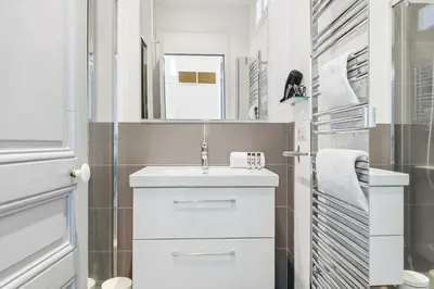 a white bathroom with a sink and a mirror at Le Rosy - Apartment in Central Cannes Balcony in Cannes