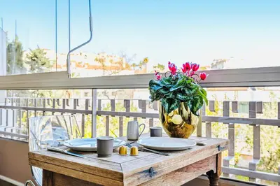 a table with plates and a vase of flowers on a balcony at Jardin Suquet - Appartement panoramique Grande terrasse vue sur mer & Palais in Cannes