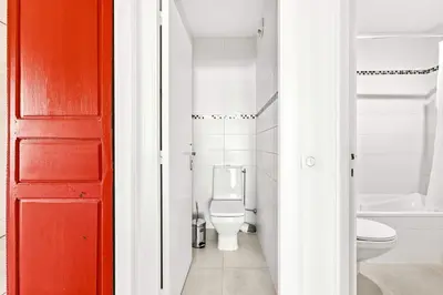 a bathroom with a toilet and a red door at Jardin Suquet - Appartement panoramique Grande terrasse vue sur mer & Palais in Cannes