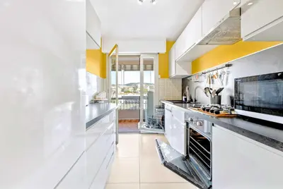 a kitchen with white appliances and yellow accents at Jardin Suquet - Appartement panoramique Grande terrasse vue sur mer & Palais in Cannes
