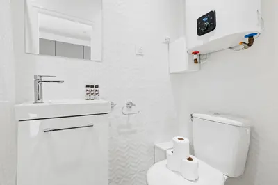 a white bathroom with a toilet and a sink at Suite Azur - Appartement en plein centre de Cannes - Climatisation - Wifi - Proche du Palais des Festivals et des Commerces in Cannes