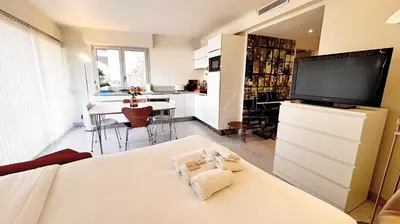 a living room with a large television and a kitchen at Pointe Croisette, 2 chambres - Exclusivité Congrès - Palmazur Vacances in Cannes