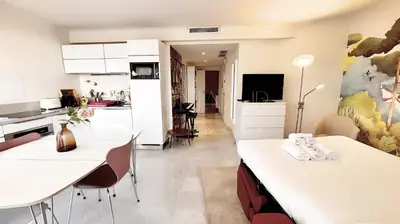 a kitchen and living room with white cabinets and a table at Pointe Croisette, 2 chambres - Exclusivité Congrès - Palmazur Vacances in Cannes