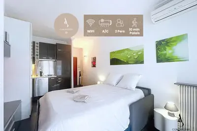 a bedroom with a large white bed and a kitchen at Le Narval - Studio - Croisette - Proche Palais in Cannes