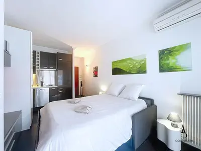 a white bed in a room with a kitchen at Le Narval - Studio - Croisette - Proche Palais in Cannes