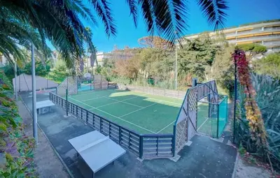 a tennis court with a net on a tennis court at Cannes, garden level, pool, nearby beaches in Cannes