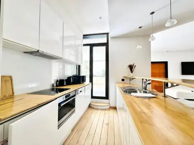 a kitchen with white cabinets and a wooden counter top at Le Gray - Terrasse Centre Cannes Croisette & Palais in Cannes