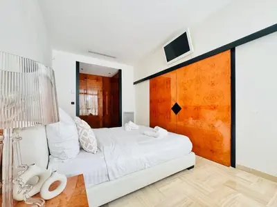 a white bedroom with a white bed and a tv at Le Gray - Terrasse Centre Cannes Croisette & Palais in Cannes