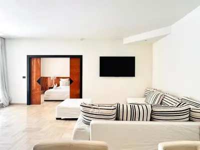 a white living room with a couch and a tv at Le Gray - Terrasse Centre Cannes Croisette & Palais in Cannes