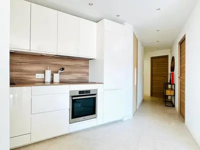 a kitchen with white cabinets and a television at Le Stanislas - Appartement 2 Chambres Terrasse in Cannes