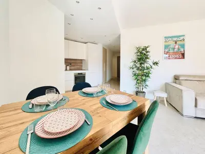 a dining room with a wooden table and green chairs at Le Stanislas - Appartement 2 Chambres Terrasse in Cannes