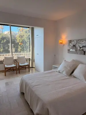 a white bedroom with a bed and a table and chairs at BELLE PLAGE, deux chambres proche mer in Cannes