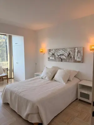 a bedroom with a white bed with a painting on the wall at BELLE PLAGE, deux chambres proche mer in Cannes