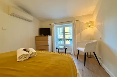 a bedroom with a yellow bed with a chair and a window at Central studio with real bed near the Palais in Cannes