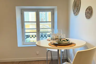 a small white table with glasses and a window at Central studio with real bed near the Palais in Cannes