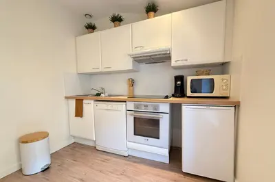 a kitchen with white cabinets and a microwave at Central studio with real bed near the Palais in Cannes