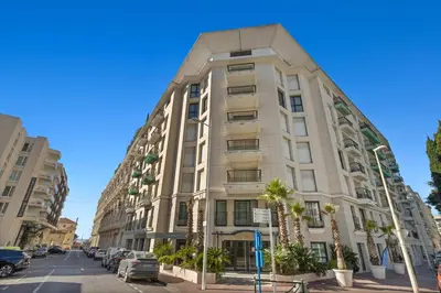 a tall white building on a city street with palm trees at Stunning 3BR apartment Carlton Riviera Croisette in Cannes