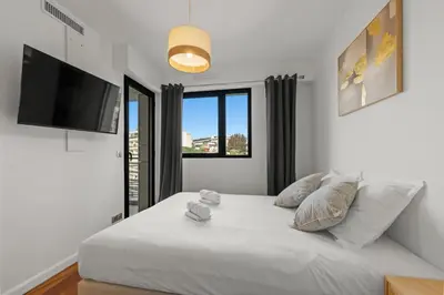 a bedroom with a large white bed with a flat screen tv at Sublime 2BR apartment Carlton Riviera Croisette in Cannes
