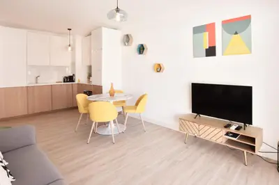 a living room with a television and a table with chairs at 1-Br with Terrace Carré dOr Walking Distance to the Beaches in Cannes