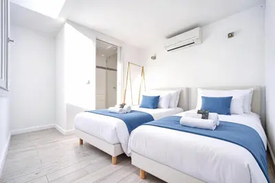 two beds in a room with white walls and wooden floors at MIPIM Walk-to-Palais 100sqm Loft 2 Ensuite Suites 3 Bathrooms Terrace Business Ready in Cannes