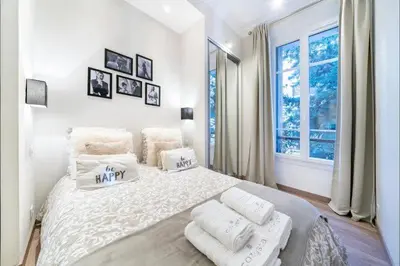 a white bedroom with a large bed with white pillows at 120 m2 GRAND STANDING CENTRE PROCHE PALAIS FESTIVALS in Cannes