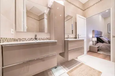 a white bathroom with a sink and a bedroom at 120 m2 GRAND STANDING CENTRE PROCHE PALAIS FESTIVALS in Cannes