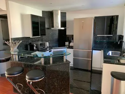 a kitchen with a glass counter with a refrigerator and stools at Villa St Marc - Standing Presta in Cannes