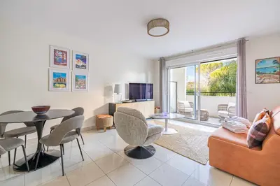 a living room with a couch and a table and chairs at Spacious Apartment a c 1BR 4P – With Pool in Cannes