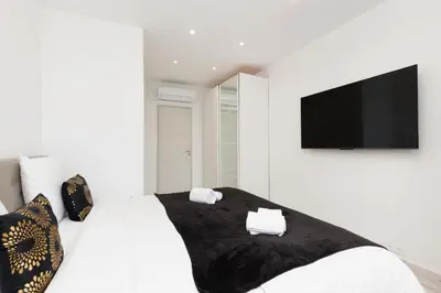 a white bedroom with a bed with a flat screen tv at Romy YourHostHelper in Cannes