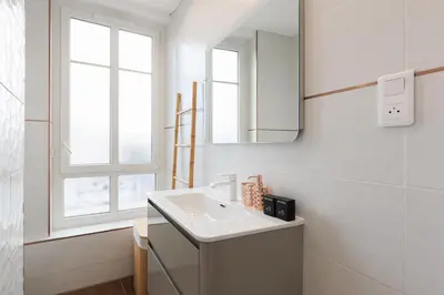 a white bathroom with a sink and a mirror at Romy YourHostHelper in Cannes