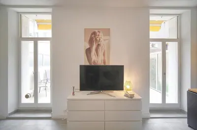 a living room with a tv on a white dresser at La Terrasse in Cannes