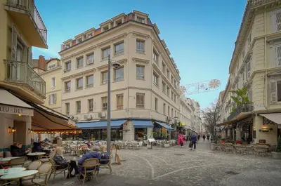 a street with people sitting at tables in front of a building at La Terrasse in Cannes