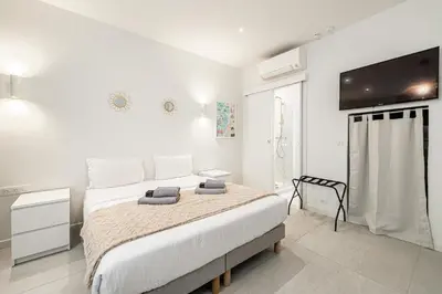 a white bedroom with a bed and a flat screen tv at 27 VAURTIN - Modern and renovated studio Cannes city centre in Cannes